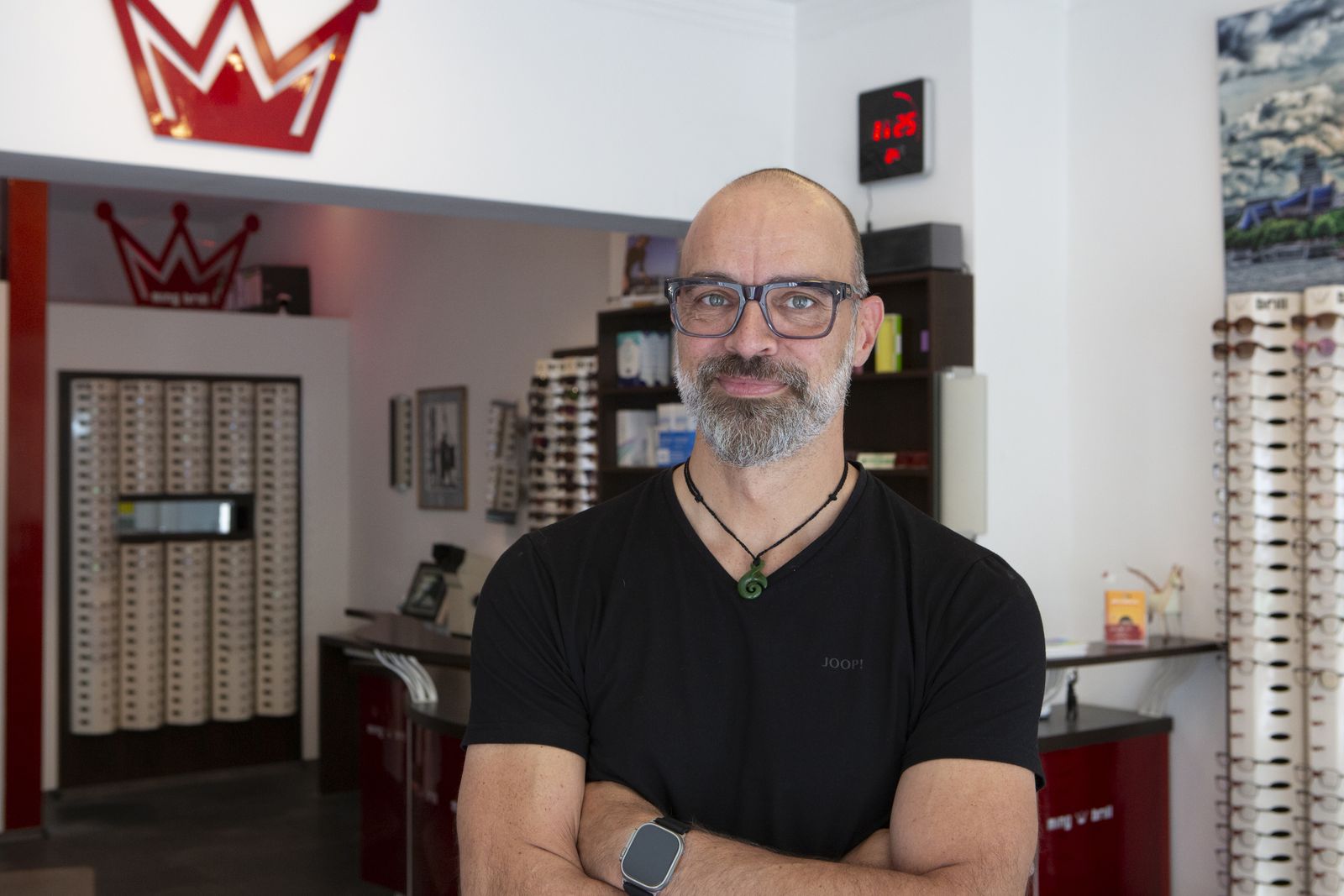 Peter Wirtz, Augenoptikermeister, mit verschränkten Armen in seinem Laden vor der roten Krone
