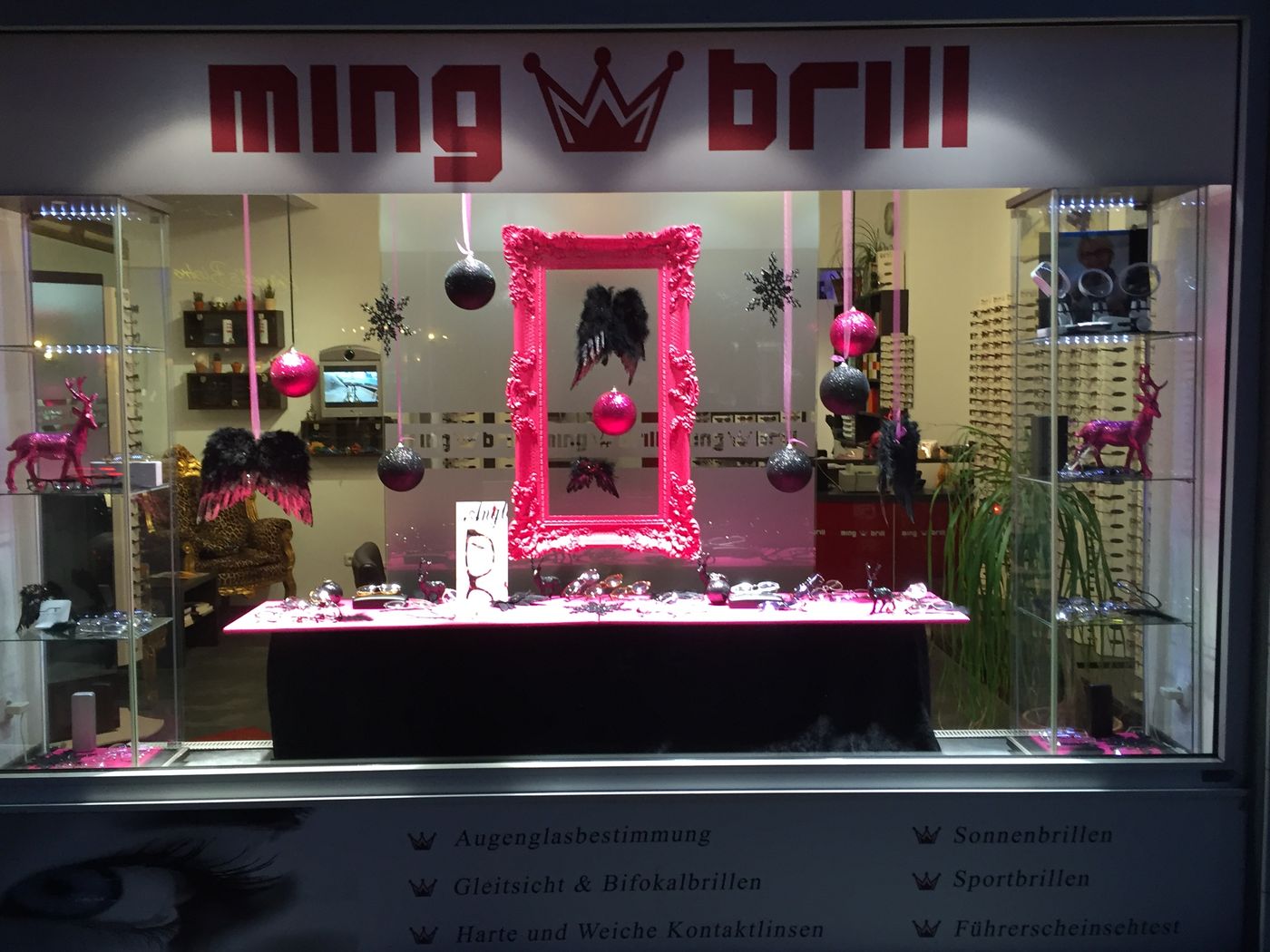 Das Schaufenster am Abend mit pinkem Barockrahmen und Weihnachtskugeln